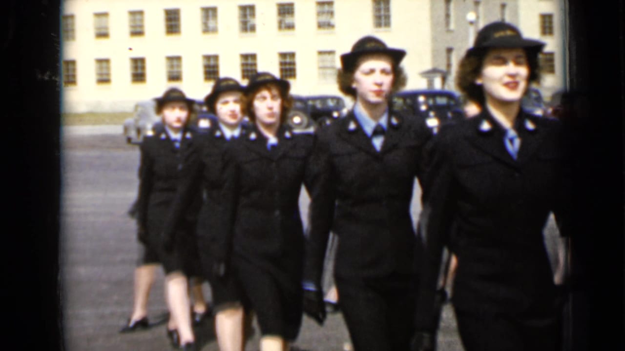 A marching formation of uniformed women moves closer to the camera.