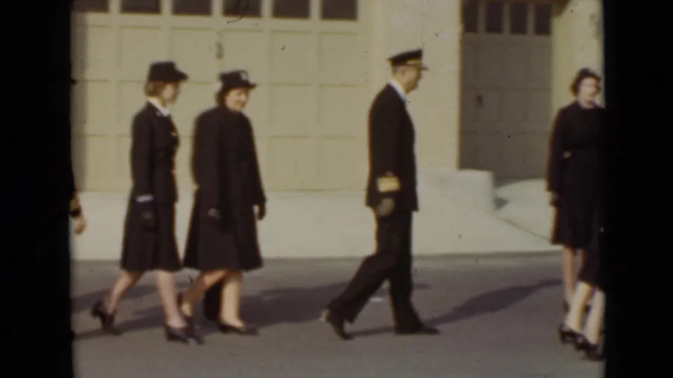 In 1947 New York, two women in matching dark coats and hats pass a man in a naval-style uniform outside.