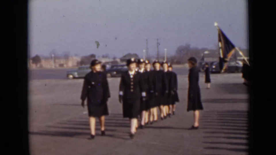 The lead women cadets pass in front of the camera during a 1947 New York drill, with the formation continuing behind them.