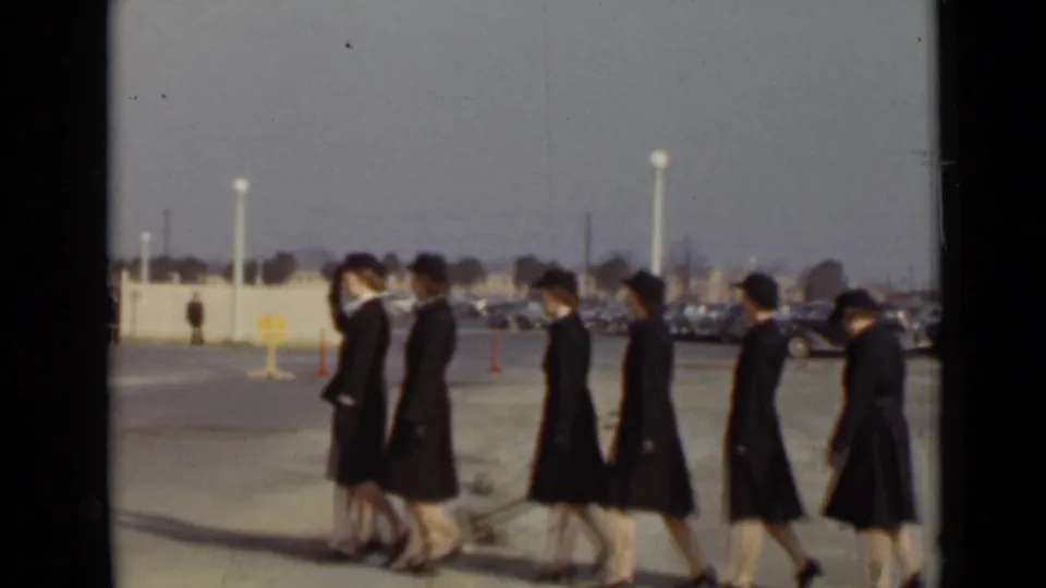 The marching line of women in dark uniforms passes through the frame during the 1947 New York outdoor ceremony.