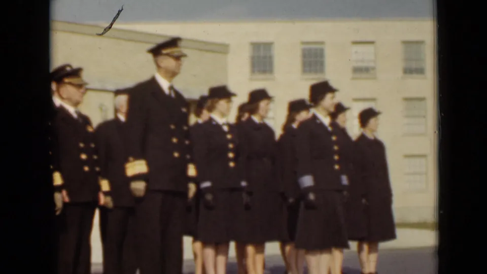 In 1947 New York footage, a male officer and women in dark military uniforms stand at attention during a formal outdoor event.