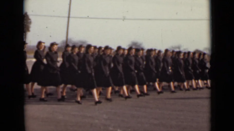 In 1947 New York footage, women in matching dark uniforms and hats march in formation across open pavement.