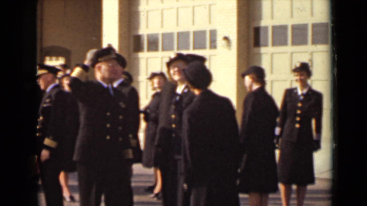 A group of uniformed men and women appears outside a New York building, with one male officer saluting near the center.