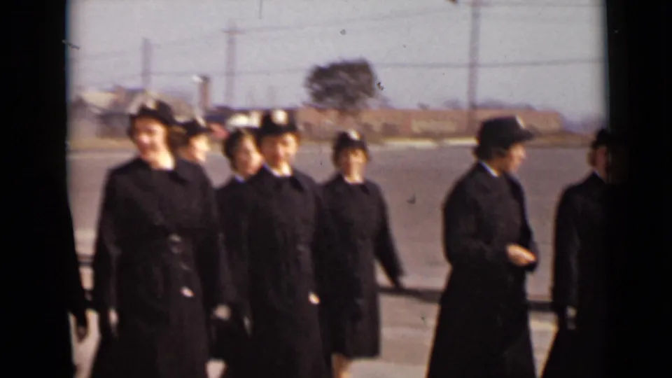 A group of uniformed women stands in loose formation on a paved parade ground or parking lot in 1947 New York footage.