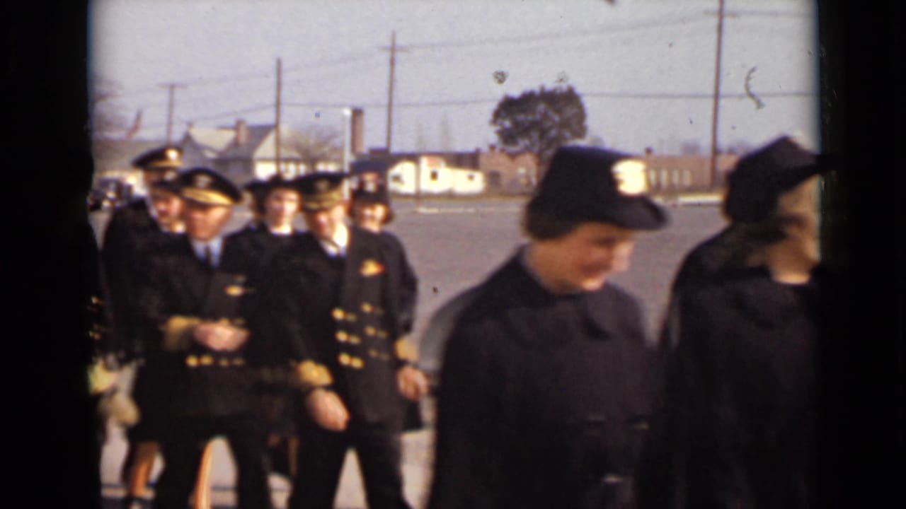 Uniformed women and male officers walk together across an outdoor lot.
