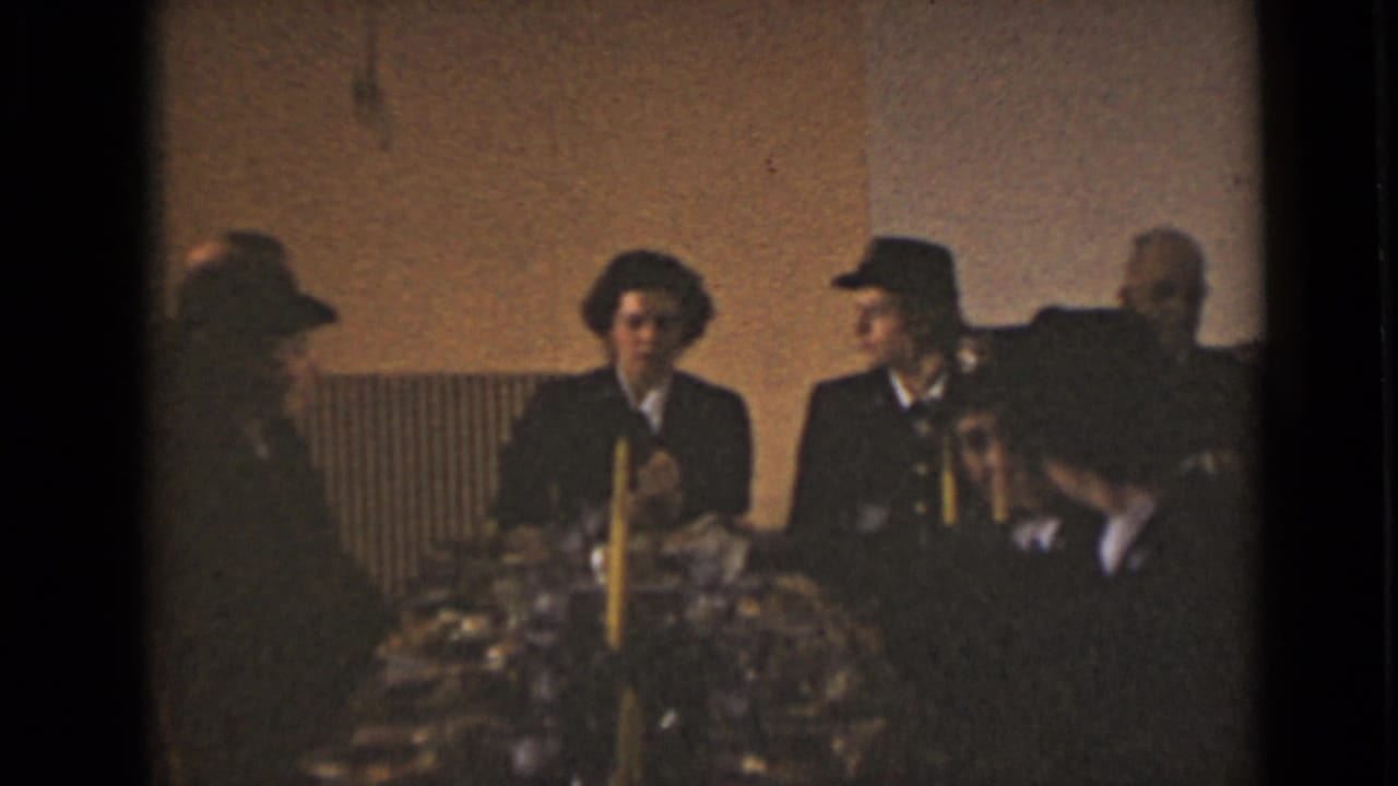 1947 New York indoor meeting scene with adults in formal dress seated beside candles and flowers.