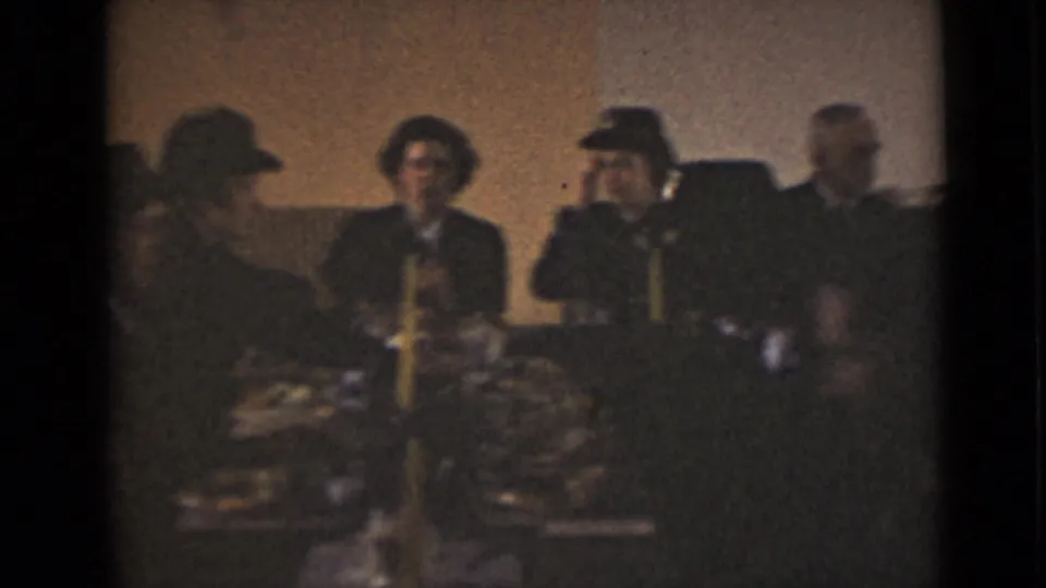 1947 New York home-movie still of formally dressed adults conversing around a decorated table.