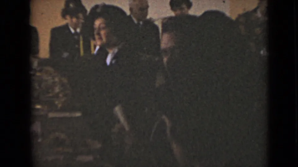 1947 New York frame with a closer, darker view of adults gathered around a decorated meeting table.