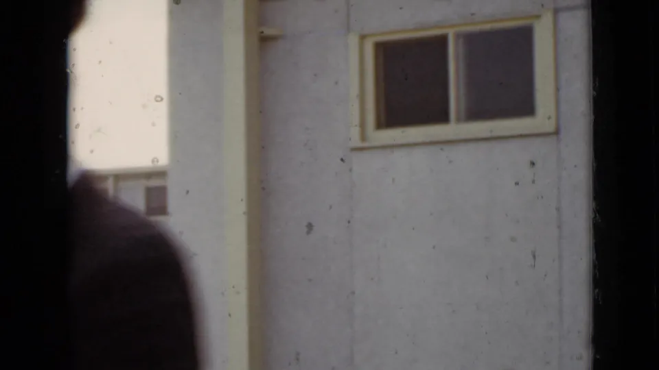1947 New York 8mm frame showing a close building wall, window, dark vertical framing, and a blurred person at the edge.