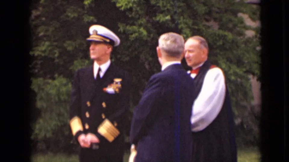 A naval officer in dress uniform stands apart while two men speak in the foreground of the 1947 New York church gathering.