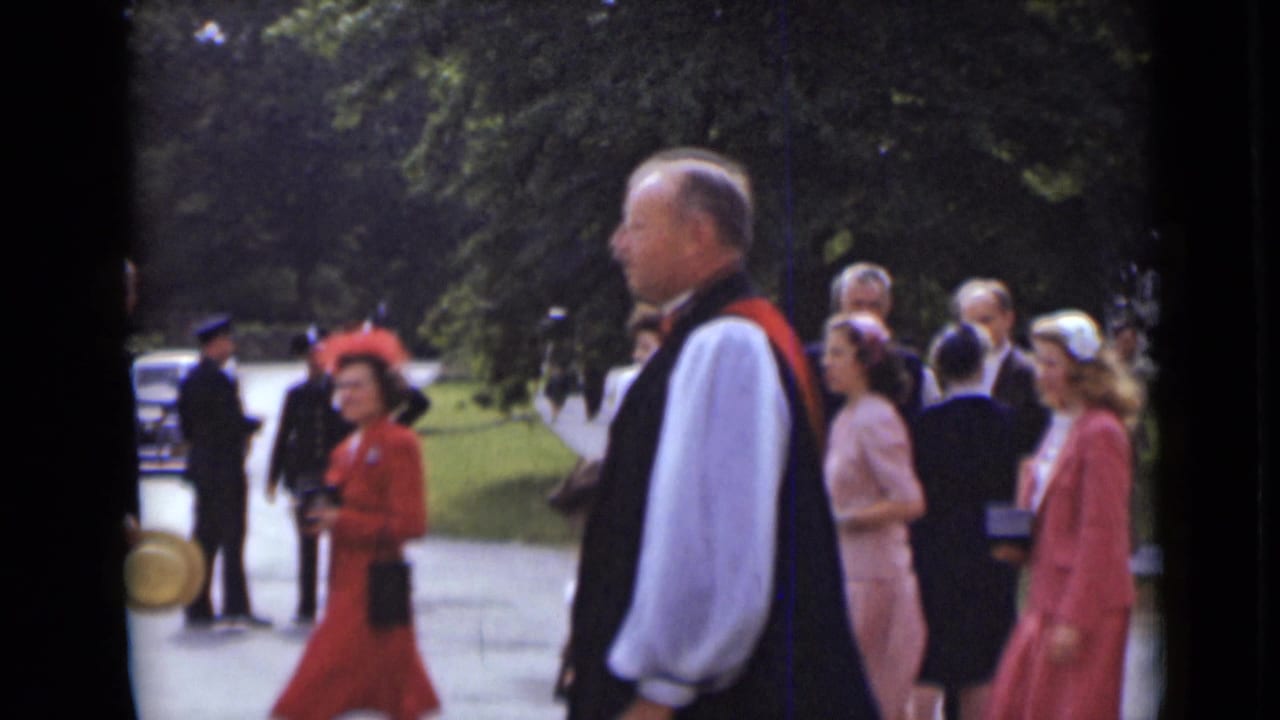 Clergy and civilians in formal dress walk along a park path.