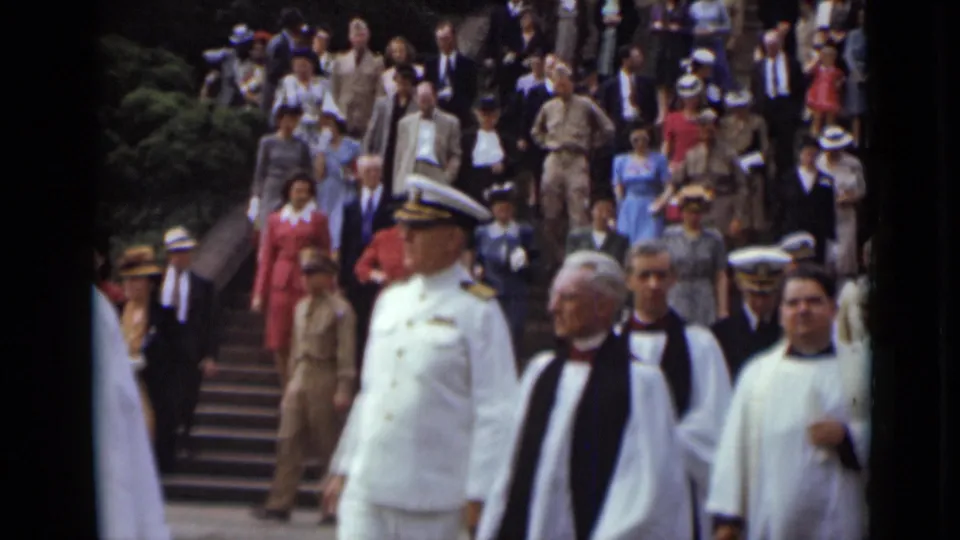 A naval-uniformed man and clergy lead a crowd down outdoor steps during a formal 1947 New York procession.