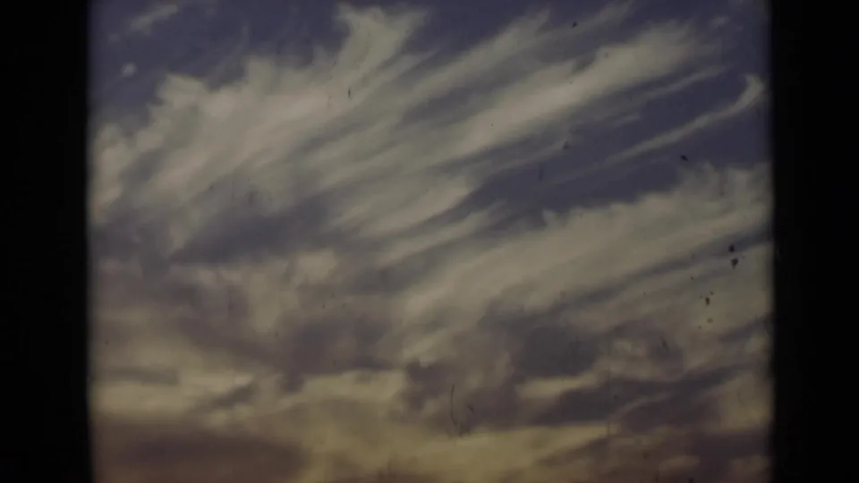 1947 New York 8mm frame of wispy cloud streaks across a blue-purple sky, with visible grain, specks, and edge darkening.