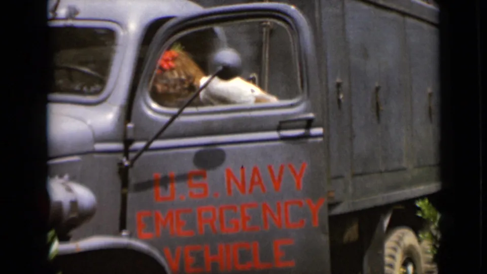 A woman leans into the cab of a U.S. Navy Emergency Vehicle, with bold red lettering visible on the side.