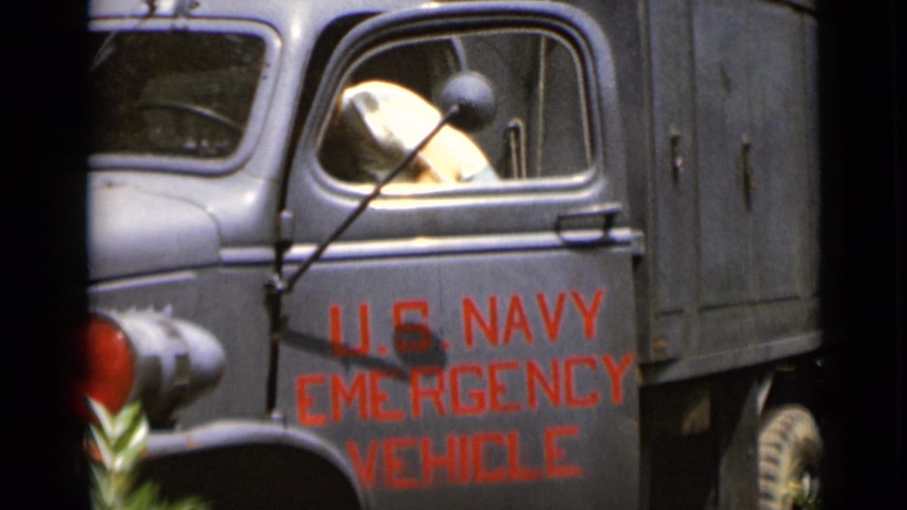 Woman in a light dress inside the open cab of a U.S. Navy emergency vehicle.