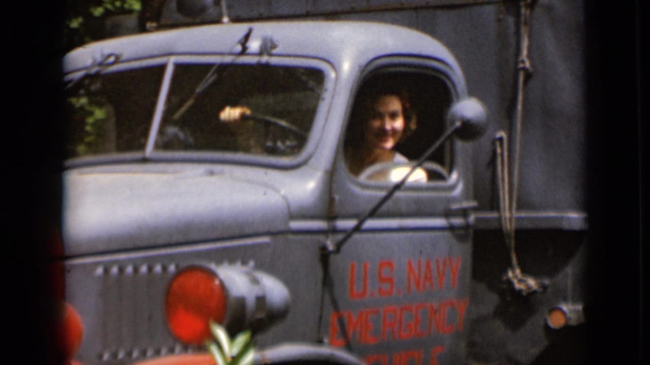 Woman smiling from the driver's window of a gray U.S. Navy emergency truck.