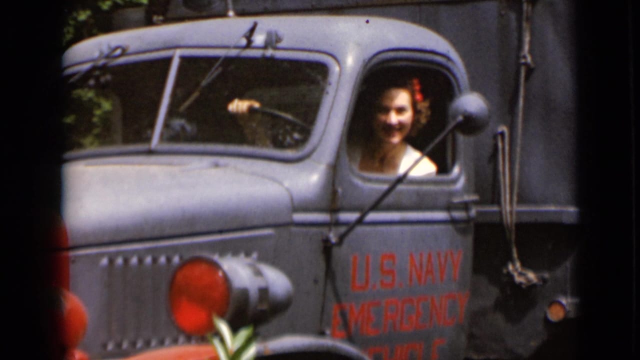 Woman with a red hair accessory smiling from a U.S. Navy emergency truck cab.
