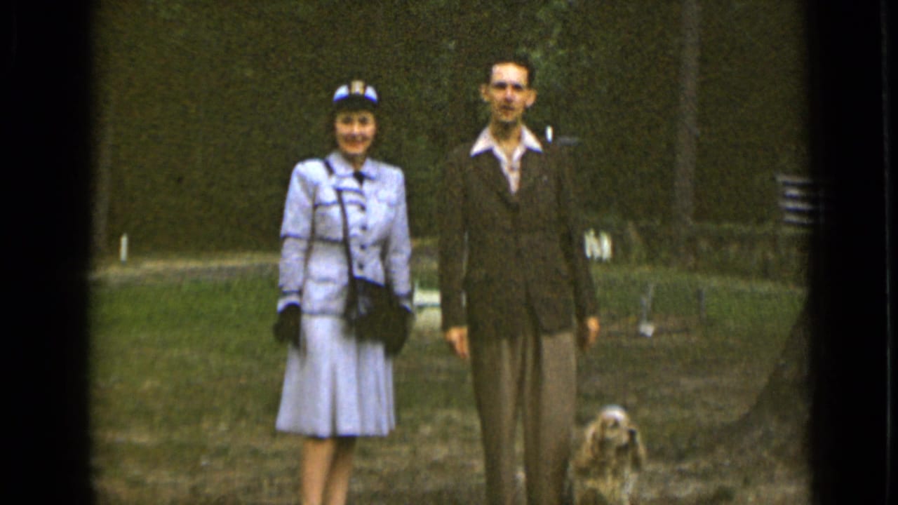 Couple faces the camera while a small dog sits low in frame.