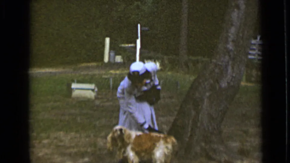 In the 1947 New York park footage, the woman bends down toward the small dog while the man is no longer in frame.