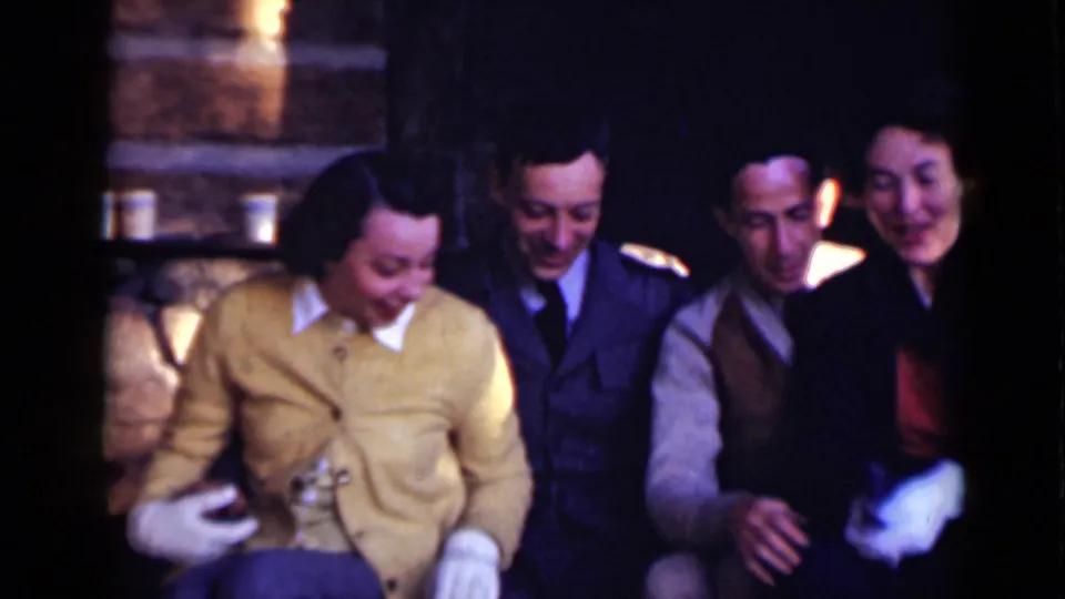 Adults in a 1947 New York interior sit shoulder to shoulder near stonework, with one woman wearing a yellow cardigan and gloves.