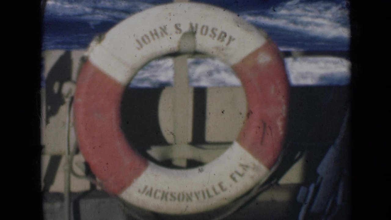 1947 8mm frame showing a red and white life preserver labeled John S Mosby and Jacksonville Fla mounted on a boat with water behind it.