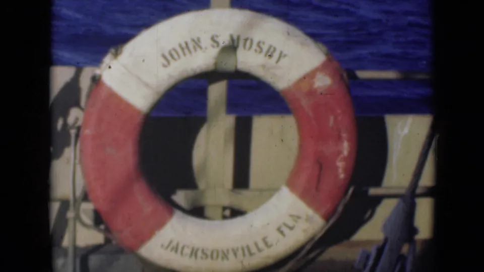 Final 8mm frame of the John S Mosby life preserver on the boat, showing Jacksonville Fla text, adjacent hardware, and rippled blue water.