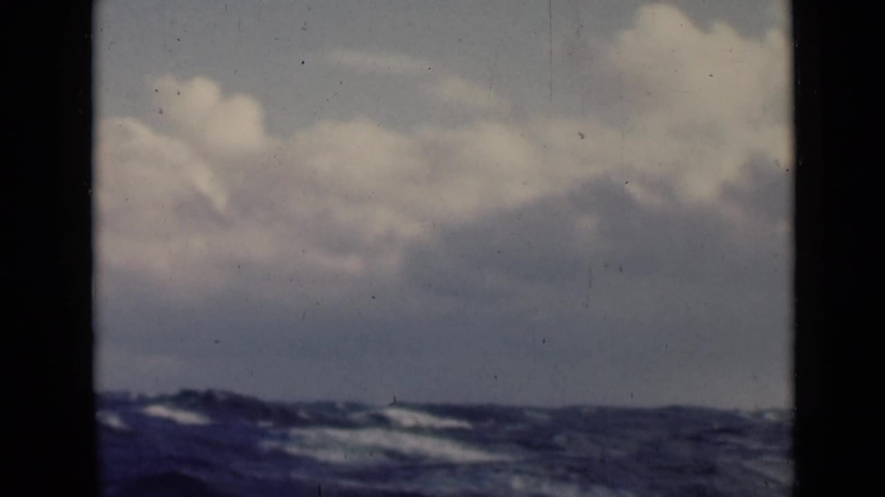 Low waves and cloudy horizon viewed through a boat window frame.