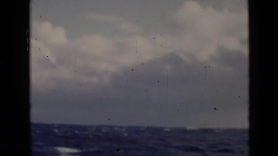 1947 home-movie view from a boat, with dark framing around cloudy sky and a rough ocean surface below.