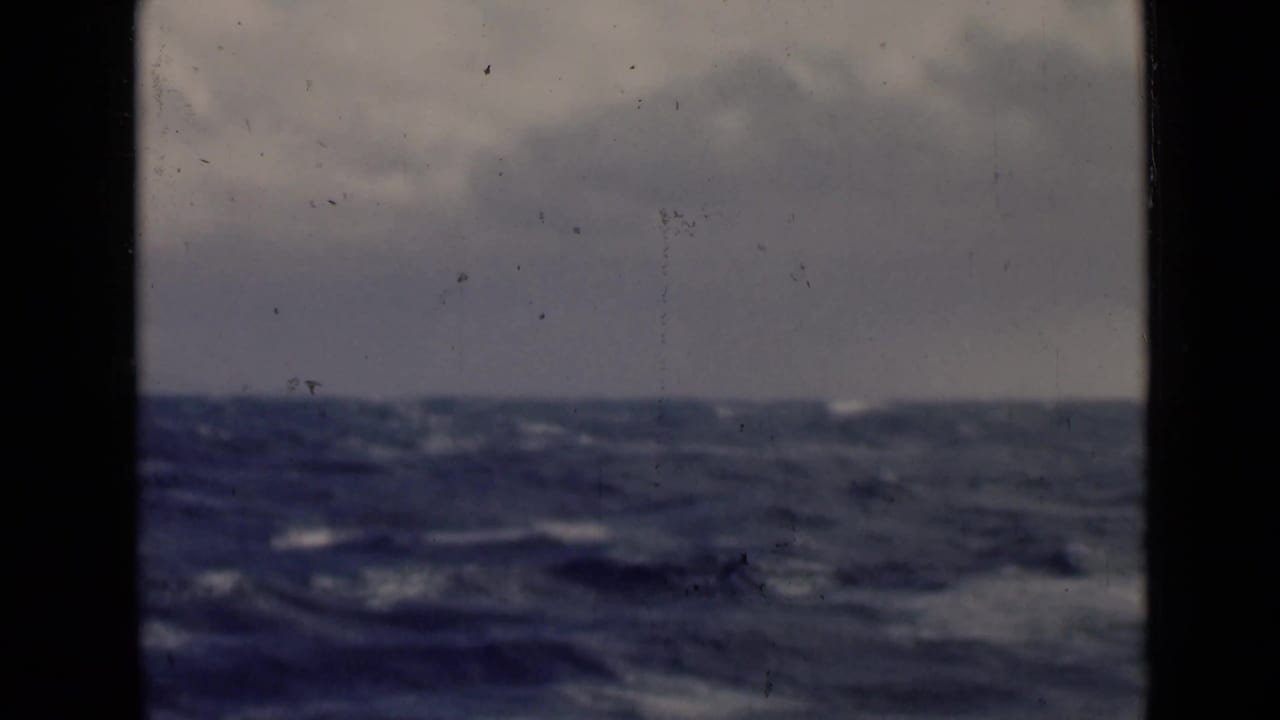 Dark rough sea under a cloudy sky with visible 8mm film borders.