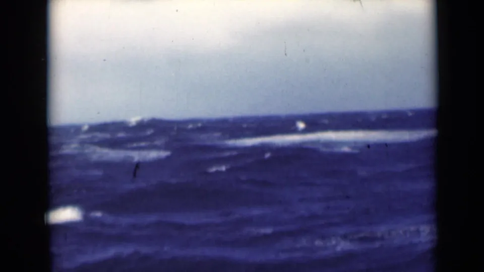 1947 8mm home-movie frame of open water, with dark waves, whitecaps, and a pale cloudy sky above a low horizon.
