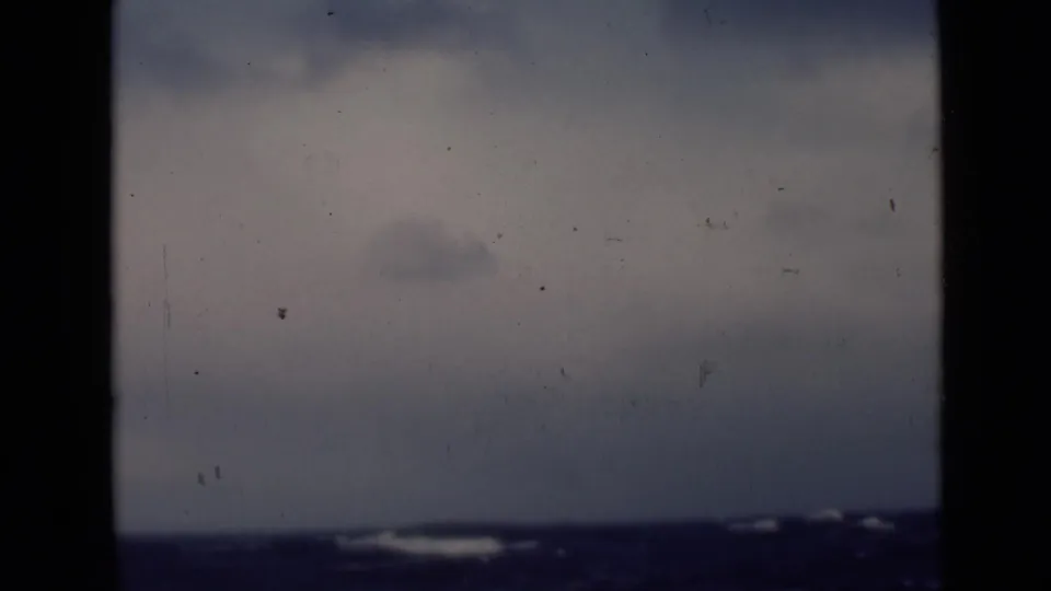 Final 8mm frame holds on open water and pale cloud cover, with dark waves and faint whitecaps near the horizon.