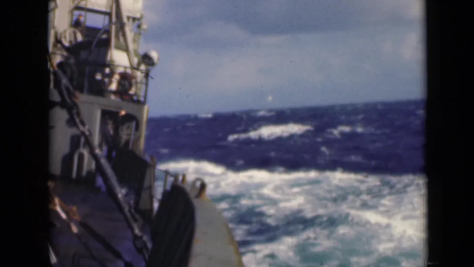 1947 8mm frame showing a deck-level view from a boat as its bow meets choppy blue water and whitecaps.