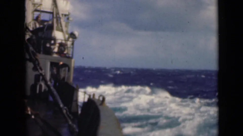 Deck-level 8mm view of a boat in choppy seas, with the side structure at left and whitecaps across the horizon.