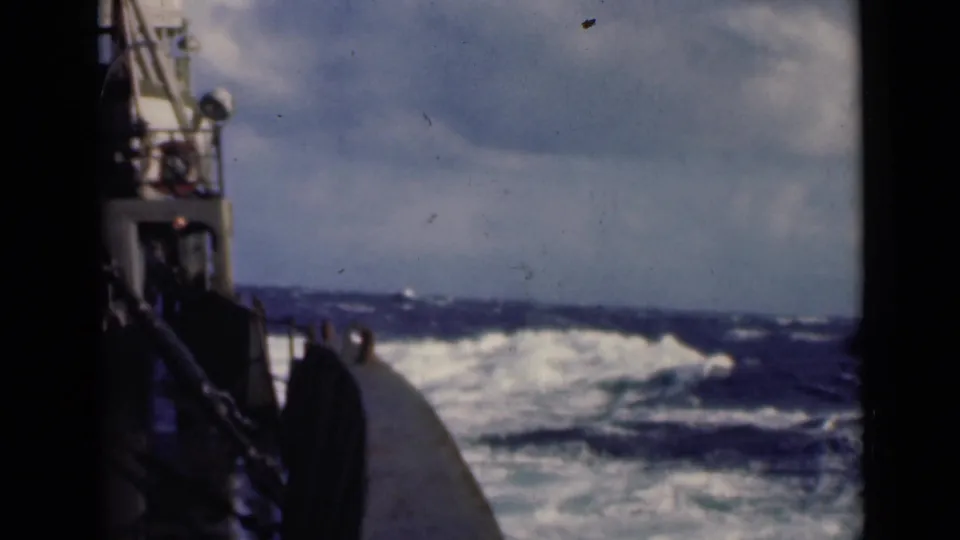 1947 home-movie frame from the boat deck, looking past the bow toward dark choppy water and low whitecaps.