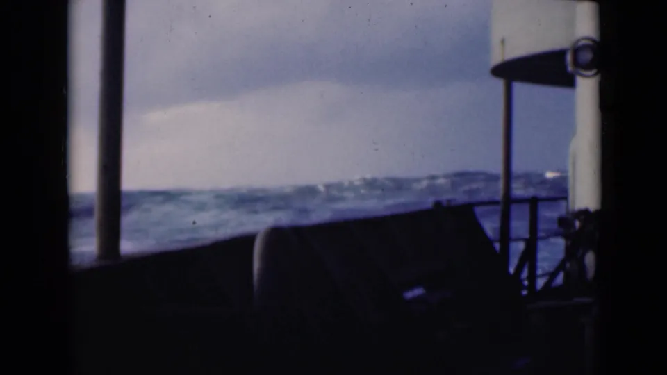 1947 8mm view from inside a boat looking toward rough blue water under an overcast sky in the Persian Gulf.