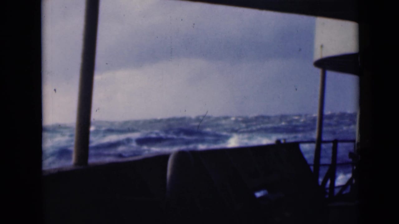 Rough ocean horizon framed by vertical boat structure and railings.
