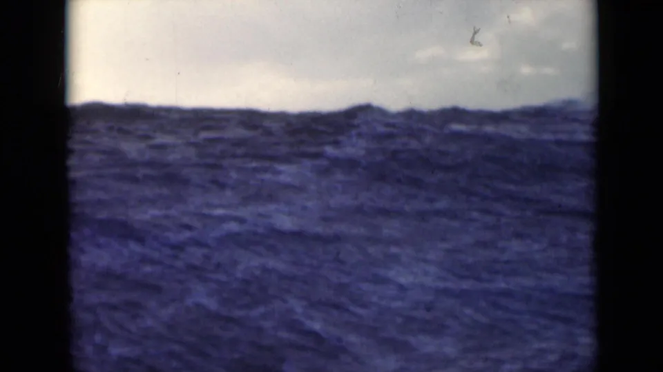1947 8mm frame showing rough open water and a cloudy horizon, likely filmed from a vessel in the Persian Gulf per clip metadata.