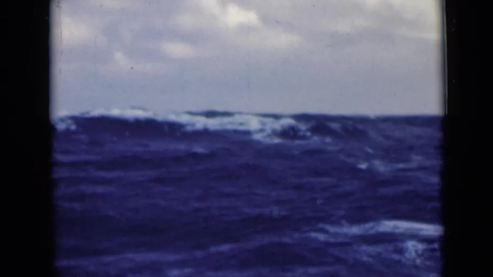 1940s 8mm frame of rough blue open water with whitecaps, a low horizon, and visible film gate edges.