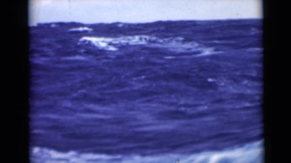 1940s 8mm frame of rolling blue sea with foam patches, soft exposure, and visible frame-edge artifacts.