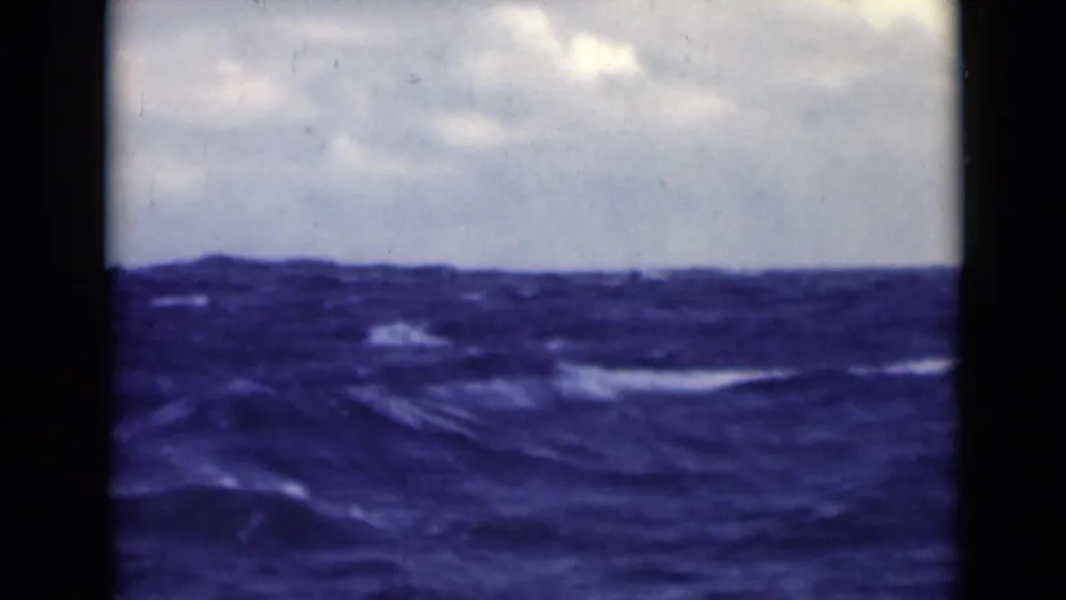 1947 8mm frame showing rough open water and a cloudy horizon from a shipboard viewpoint.