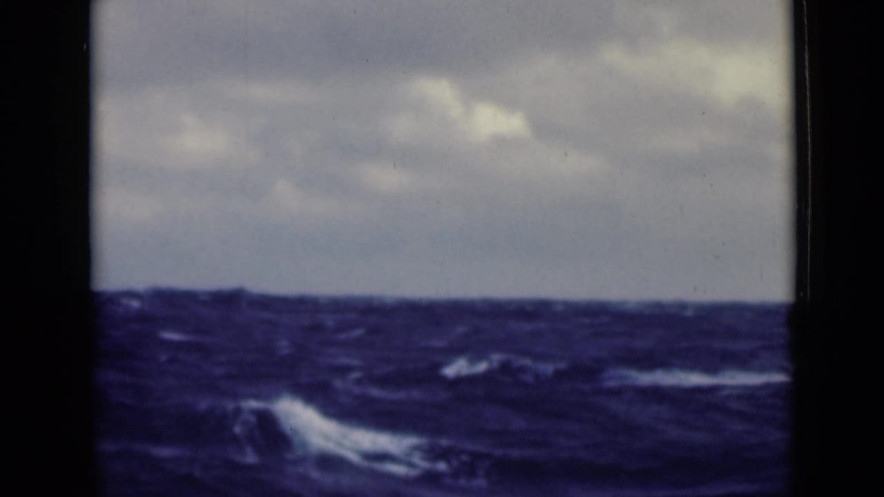 Rough sea with whitecaps beneath a cloudy sky and black frame borders.