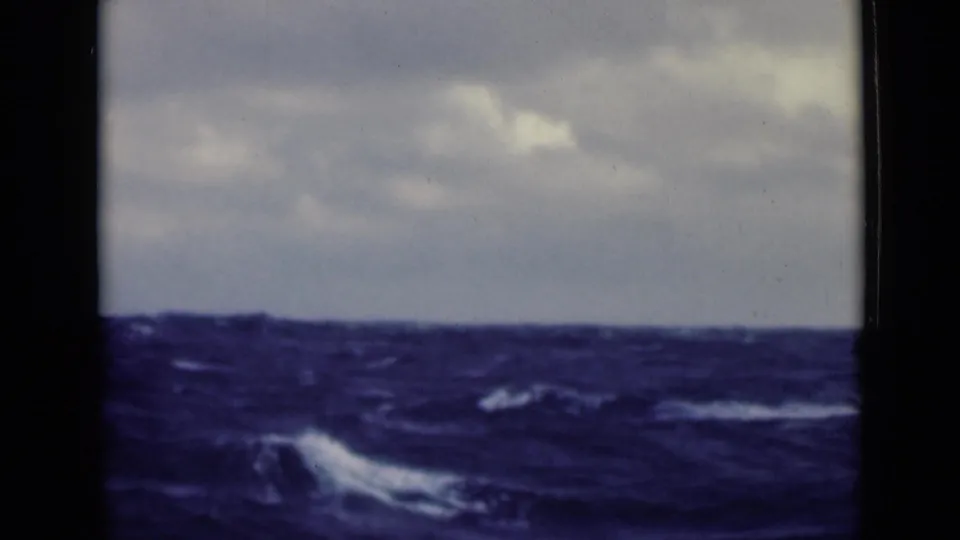 Open water appears choppy in this 8mm shipboard view, with whitecaps beneath an overcast sky.