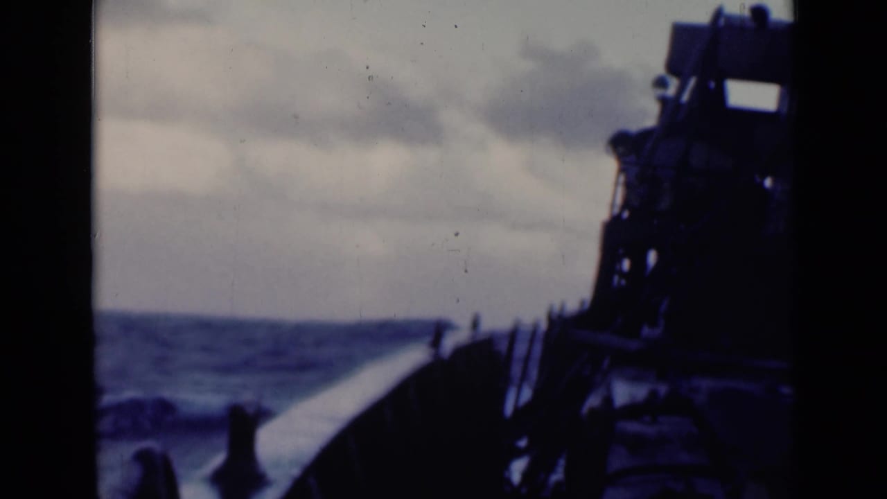 Rough sea seen from a ship deck with dark vessel structure on the right.