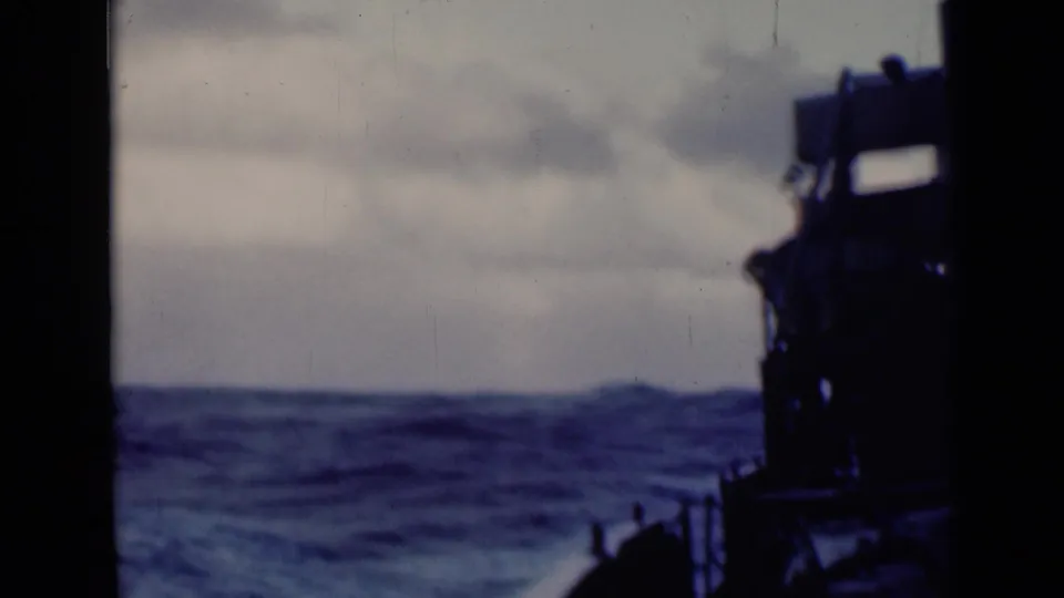 1947 8mm frame emphasizing rolling open water, with the ship's dark side structure partly visible along the right edge.