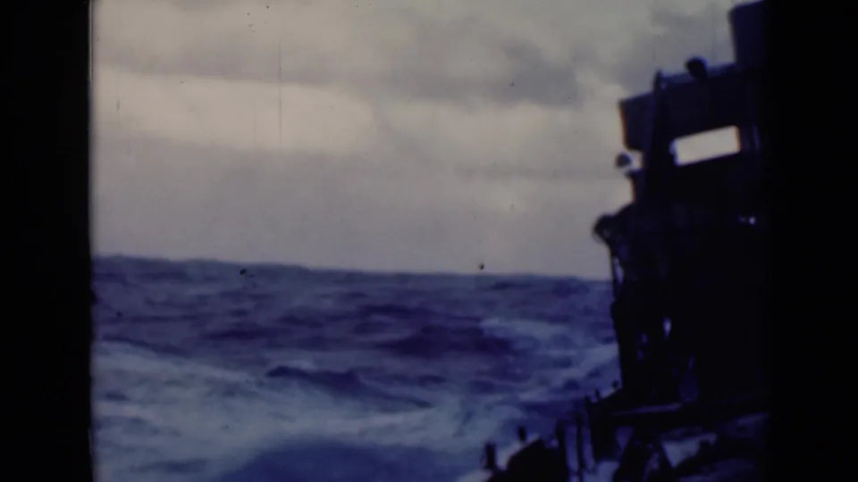 1947 8mm frame showing rough sea beyond the ship's dark superstructure, with soft focus and visible film wear.