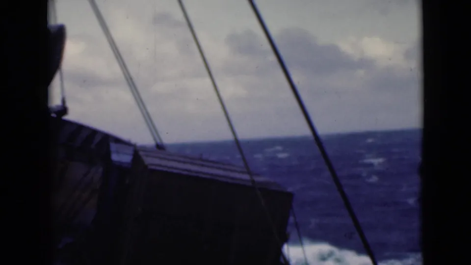 1940s 8mm deck view with dark rigging, ship structure, rough sea, and overcast sky in soft color film.