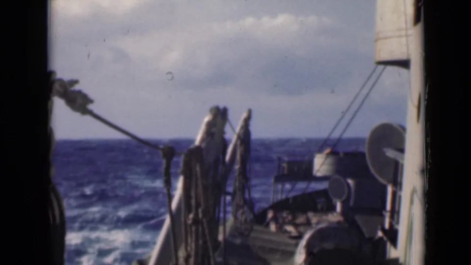 1947 8mm frame showing a ship deck edge, rigging, and hardware as the vessel moves through white-capped water.