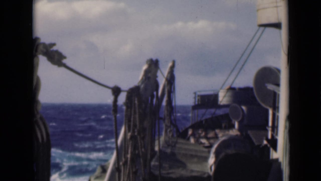 Ship deck ropes and equipment seen against choppy blue water and cloudy sky.