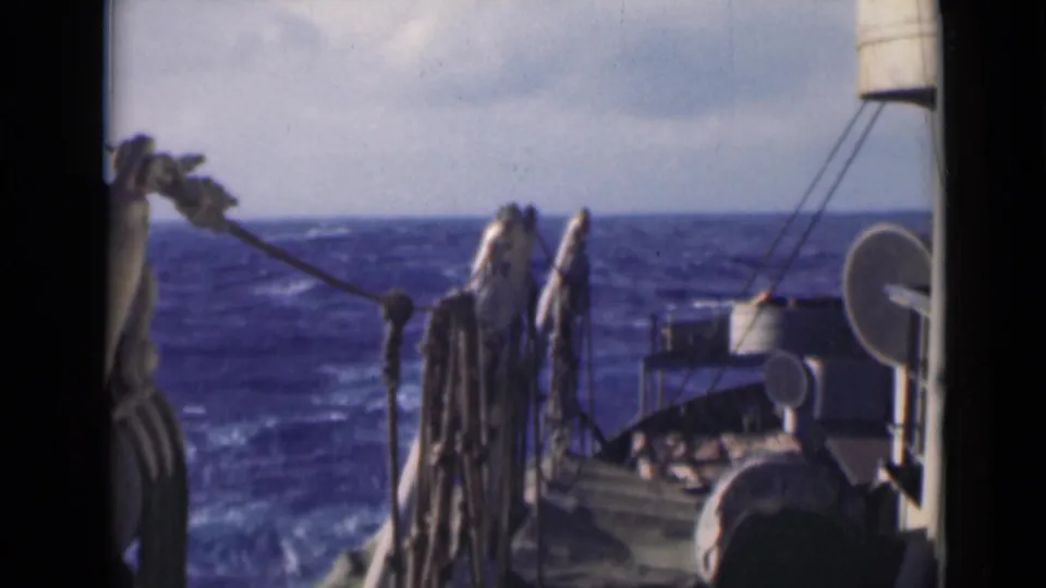 Final 8mm frame of a vessel deck at sea, showing rigging, hanging ropes, deck fixtures, and a choppy horizon.