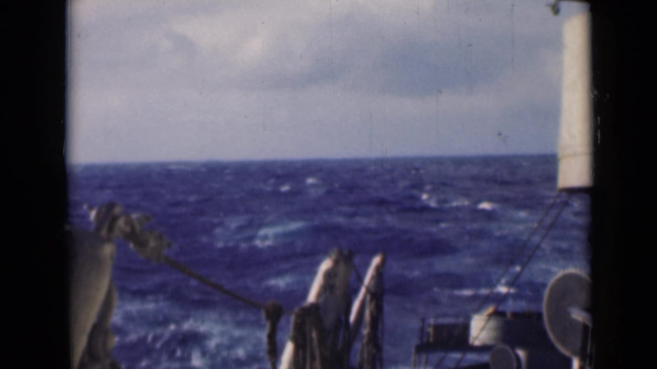 Open blue water with whitecaps viewed past ship rigging and deck equipment.